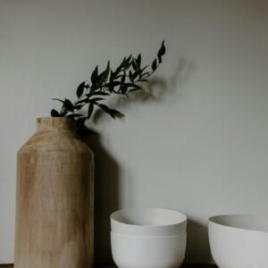 A minimalist kitchen setup featuring a wooden vase with greenery and two white ceramic bowls