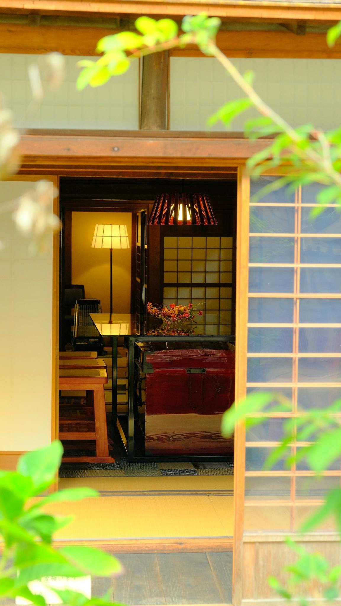 View into a traditional Japanese room through a wooden entrance, featuring shoji screens.